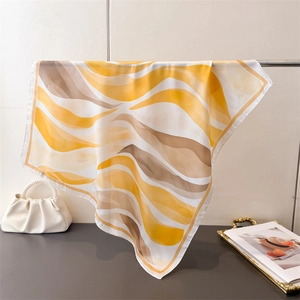 Détail du drapé d'un foulard carré en soie artificielle aux motifs de vagues jaunes