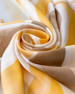 Gros plan d'un foulard en soie aux rayures dégradées jaunes et marron satinées