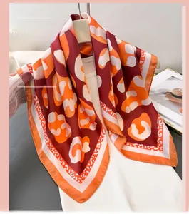 Detail of burgundy leopard print silk scarf with artistic geometric patterns and borders
