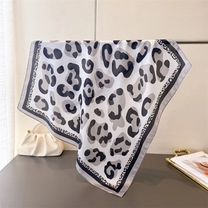 Detail of leopard print silk scarf draped over a metal rack with fashion accessories