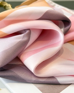 Vue macro du tissu d'un foulard en soie montrant des motifs géométriques roses lisses