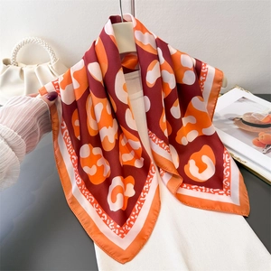 Elegant leopard print silk scarf with abstract orange and burgundy patterns on white knit top