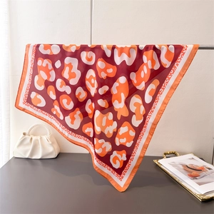 Detail view of red leopard print silk scarf draped elegantly on a metal stand