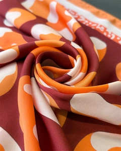 Detail of burgundy and orange leopard silk scarf showing premium fabric sheen and texture