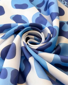 Detail of blue and white abstract leopard print silk scarf with spiral folded texture