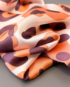 Close-up of leopard print silk scarf showing soft fabric texture and vibrant orange patterns