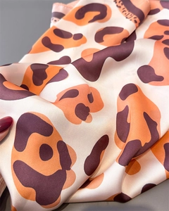 Close-up detail of leopard print silk scarf with luxury texture and glossy finish
