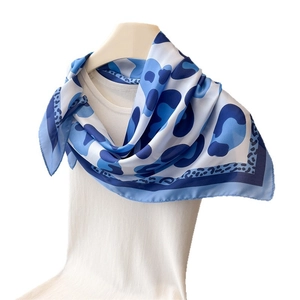 Blue and white leopard print silk-like scarf with polka dot borders on a white tank top