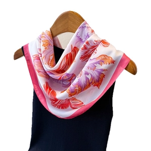 Elegant silk scarf with abstract floral print and pink borders on a black top