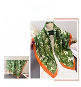 Detail showing grass green silk scarf with cartoon animal prints and orange edges