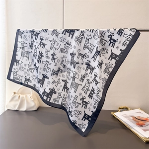 Detail of silk scarf with hand-drawn animal prints and black borders hanging on a rack