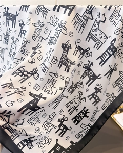 Detailed view of silk-like scarf featuring hand-drawn graffiti animal patterns and black border
