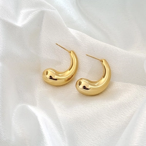 Polished 18K gold-plated irregular hollow teardrop earrings on white silk fabric