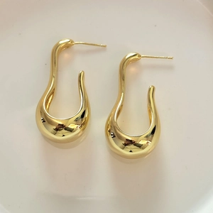 Detail view of gold U-shaped curved earrings with a polished minimalist aesthetic