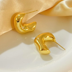 Polished 18K gold plated C-shaped chunky hoop earrings on white ceramic dish