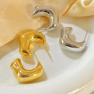 Detail view of gold and silver chunky geometric hoop earrings on a silk background