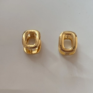 Detailed view of chunky golden oval hoop earrings with mirror polished metallic surface