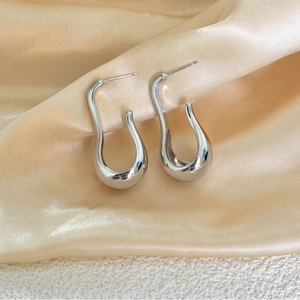 Minimalist silver U-shaped oval teardrop earrings on elegant champagne silk fabric background