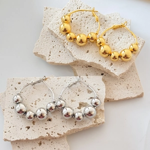 Polished 18K gold and silver hoop earrings with gradient metal beads on stone