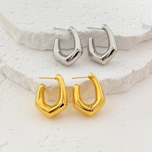 Polished silver and gold geometric U-shaped hollow earrings on a textured stone surface