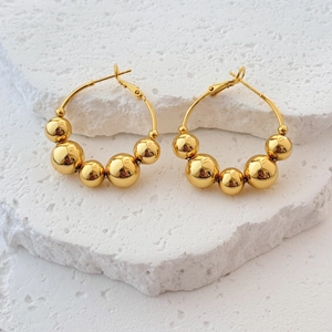 Polished 18K gold-plated large hoop earrings with graduated metal beads on white stone
