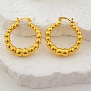 Créoles creuses plaquées or 18 carats avec texture bulle sur fond de pierre blanche