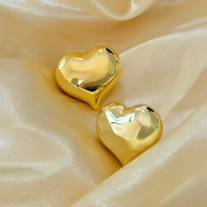 Polished 18K gold plated oversized hollow heart earrings on champagne satin background