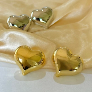 Polished oversized hollow heart earrings in gold and silver finish on silk fabric