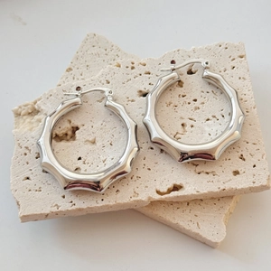 Vue macro de boucles d'oreilles créoles dorées 18 carats texture bambou sur pierre