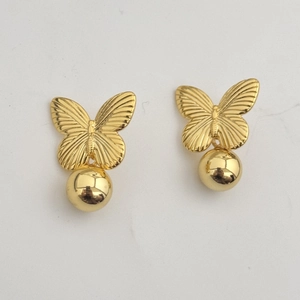 Détail de boucles d'oreilles papillon dorées avec une breloque sphérique en métal brillant