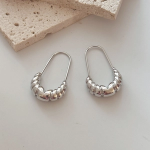 Minimalist silver U-shaped earrings with ribbed croissant texture on a stone background