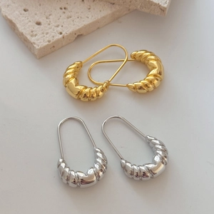Minimalist French style gold and silver U-shaped twist hoop earrings on a stone base
