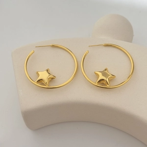 Minimalist large gold star hoop earrings with high polish finish on a white pedestal