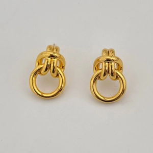 Detail of gold-plated knot stud earrings featuring a smooth metal loop on white background