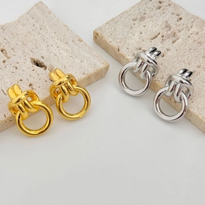 Minimalist gold and silver knotted metal drop earrings on decorative stone display