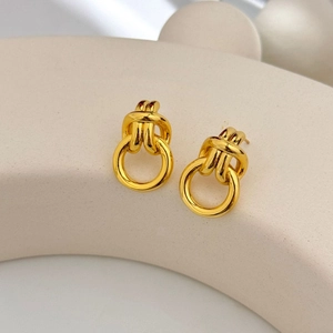 Close-up of golden knot stud earrings on a geometric display for a modern aesthetic