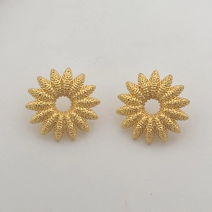 Detail of matte gold sunburst stud earrings with textured petals and floral design