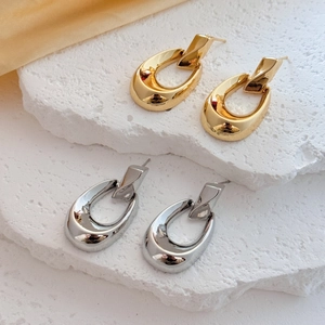 Boucles d'oreilles ovales minimalistes en métal poli doré et argenté sur roche blanche