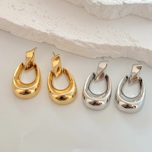 Détail de boucles d'oreilles pendantes géométriques en forme de U en or et argent polis