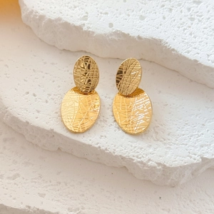 Modern gold double oval earrings with textured geometric design on stone steps