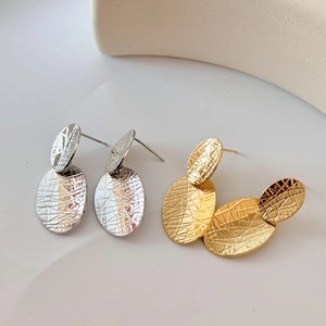 Detail of gold and silver layered oval earrings with textured hammered finish style