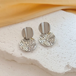 Detail of silver wavy disk earrings with textured hollow mesh on a stone stand