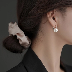 Elegant geometric pearl drop earrings with silver hooks shown in a side-view portrait