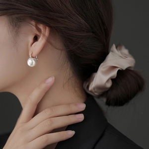 Elegant geometric pearl earrings with silver clasp on a model in black suit