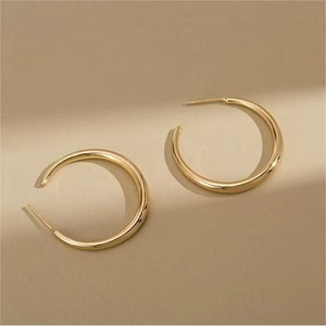 Detailed view of polished gold C-shape hoop earrings with minimalist metal texture