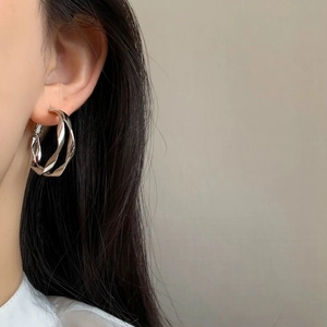 Silver geometric twisted double-layer hoop earrings for women shown on a model
