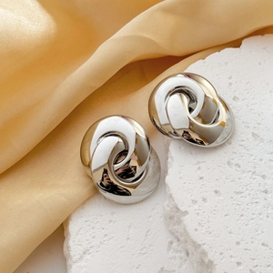 Minimalist silver interlocking geometric hoop earrings on elegant textured stone and silk