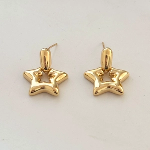Detailed view of gold star-shaped hollow drop earrings with polished metallic finish