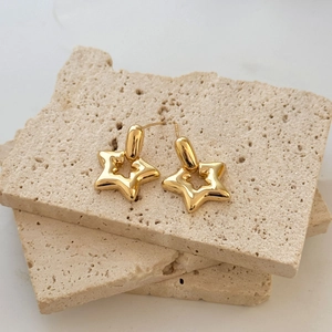 Polished gold hollow star earrings with S925 silver needles on a textured stone background