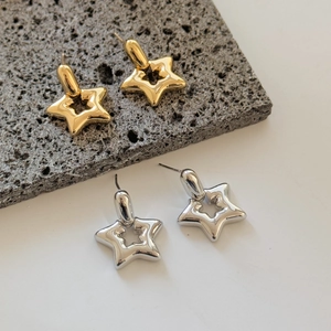 Polished hollow star stud earrings in gold and silver finish on a mineral background